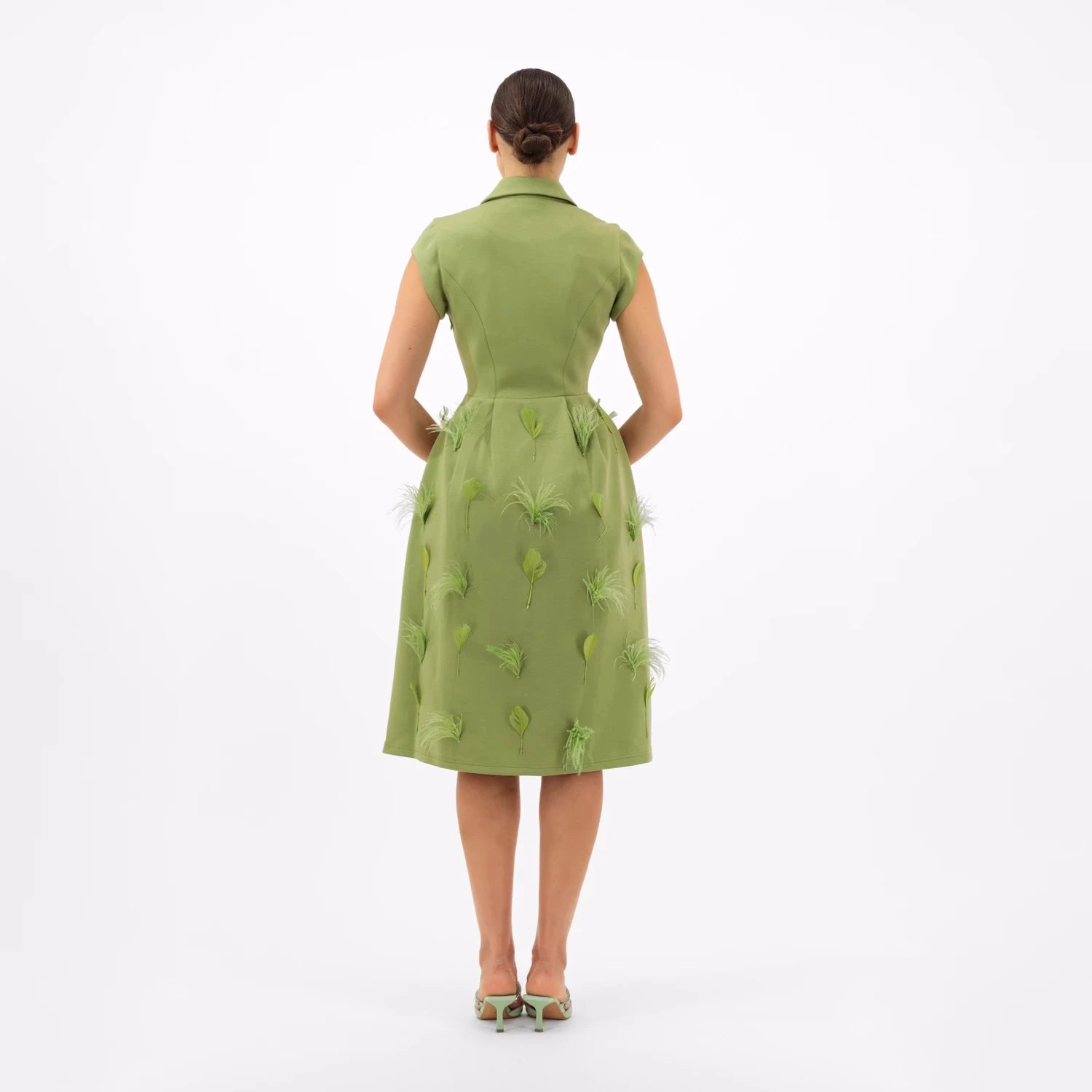 Rear view of a woman wearing a pale green dress featuring a fitted bodice and a full skirt with deli