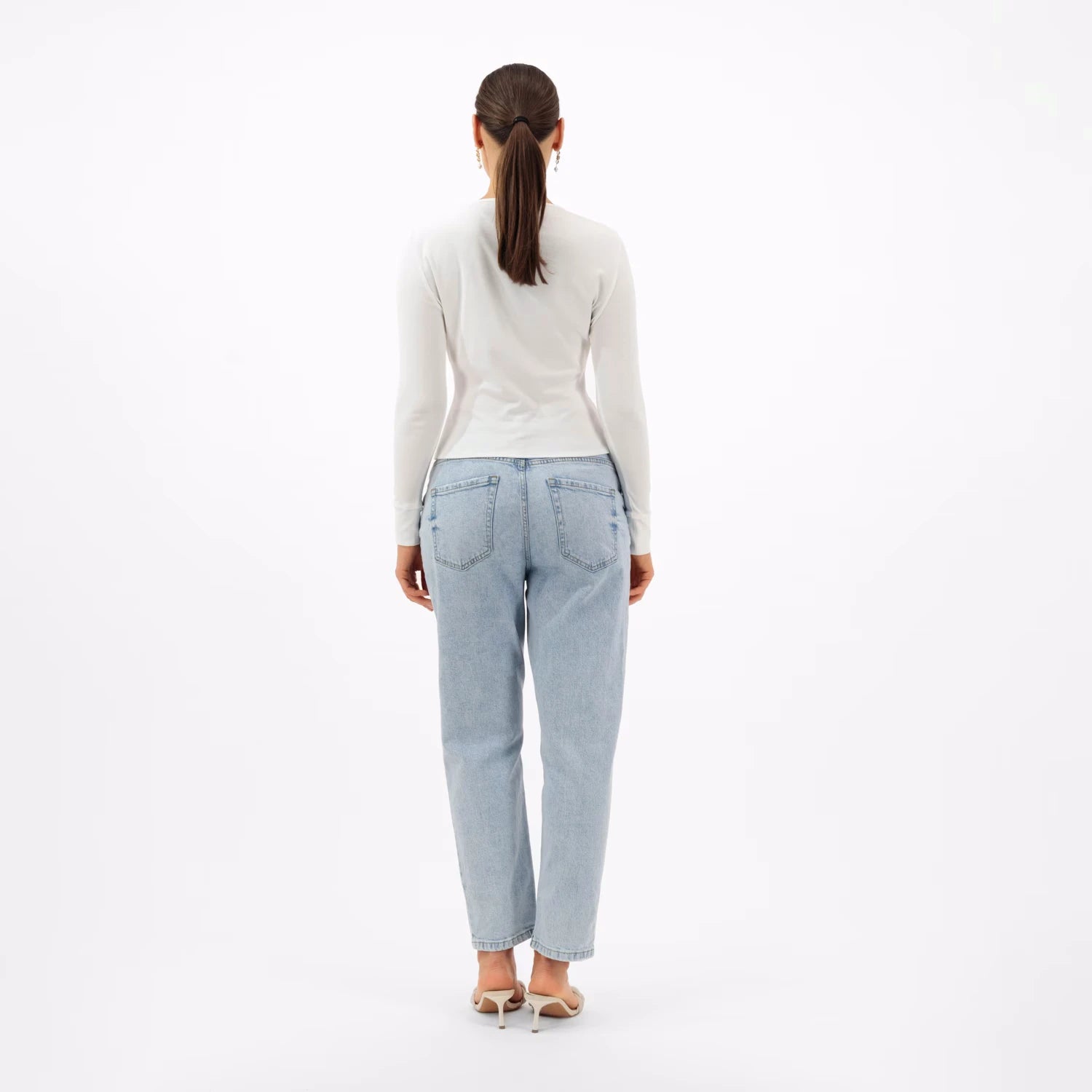 An Old Money inspired look with a simple white top and light-wash jeans, viewed from the back.
