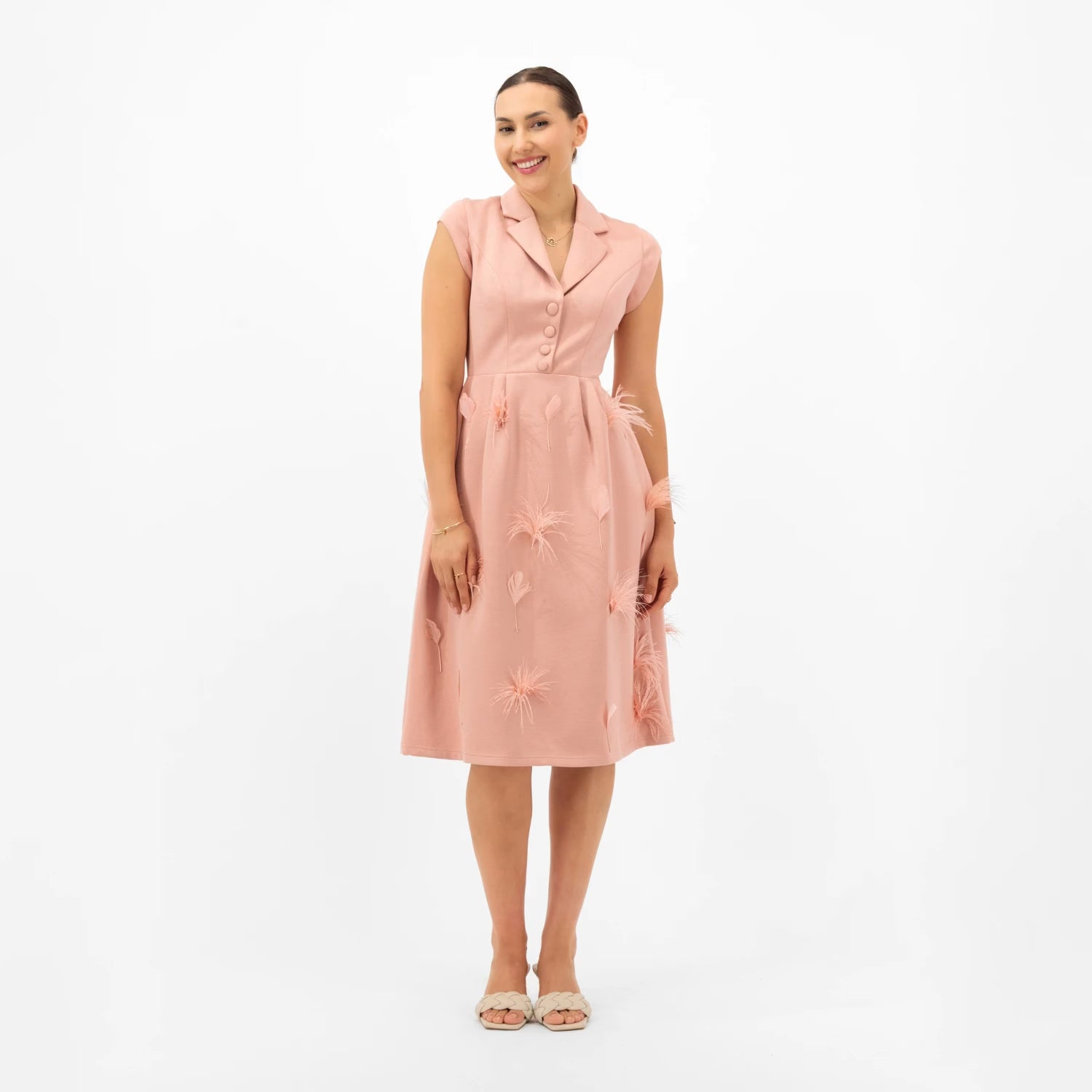 Woman wearing a pink dress with floral embroidery on a white background
