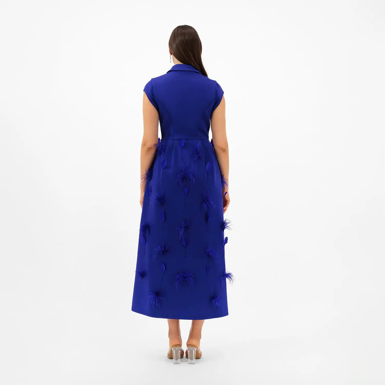 Woman wearing a blue dress with feather details on a white background